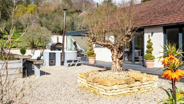 A modern house with a stone-built garden, a barbecue area, and a large tree. - Stunning 1 BD Home in Worcestershire (Worcester)