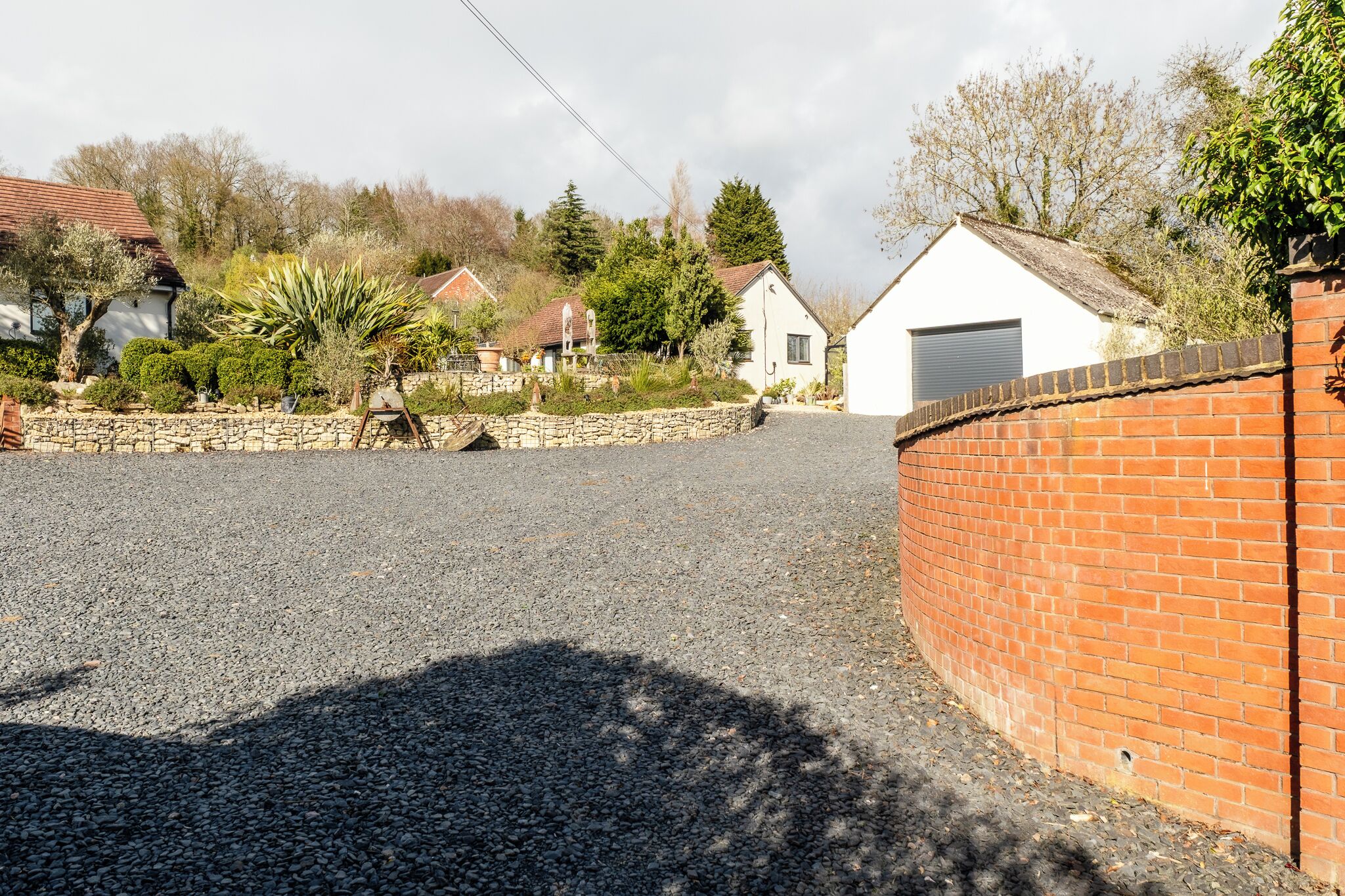 A residential area with a gravel driveway, stone wall, and a brick wall.
