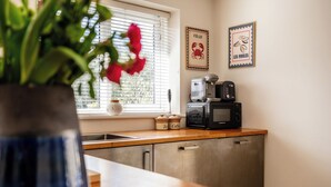 A kitchen with a microwave, coffee maker, and a window with blinds. - Stunning 1 BD Home in Worcestershire (Worcester)