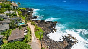 A coastal residential area with houses, a clear view of the ocean, and a rocky shoreline. - Honu Kai Villa 1 by Alekona Kauai: Luxury 3BR Oceanfront home with resort amenities (Koloa)