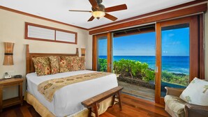 A bedroom with a large bed, a ceiling fan, a view of the ocean, and a wooden floor. - Honu Kai Villa 1 by Alekona Kauai: Luxury 3BR Oceanfront home with resort amenities (Koloa)