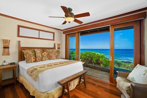 A bedroom with a large bed, a ceiling fan, a view of the ocean, and a wooden floor. - Honu Kai Villa 1 by Alekona Kauai: Luxury 3BR Oceanfront home with resort amenities (Koloa)