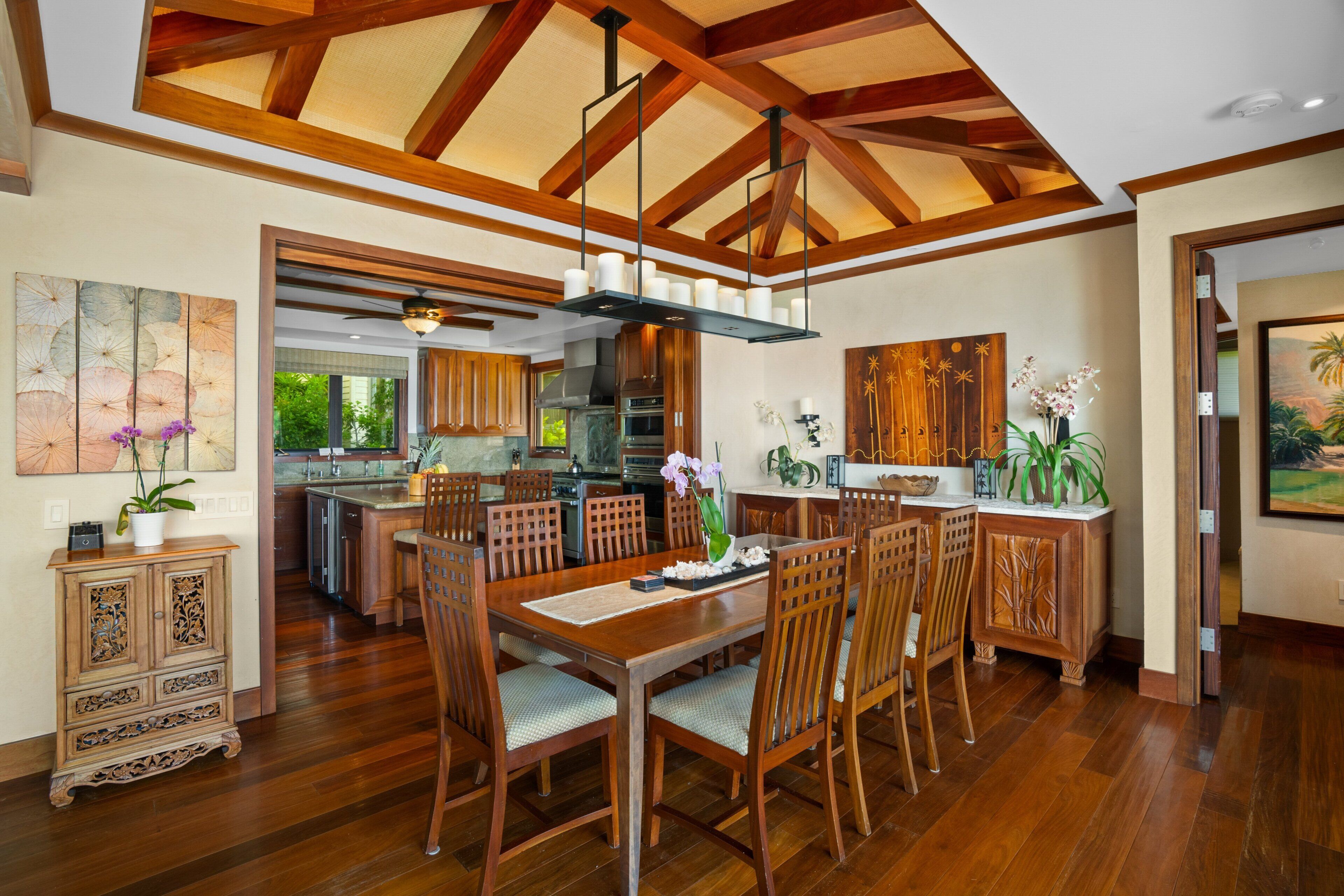 Une cuisine spacieuse avec des meubles de rangement en bois, un coin repas avec une table et des chaises en bois, et un plafond avec des poutres apparentes.