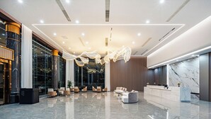 Un hall d’entrée moderne avec un comptoir d’accueil, un espace salon et de grandes fenêtres.