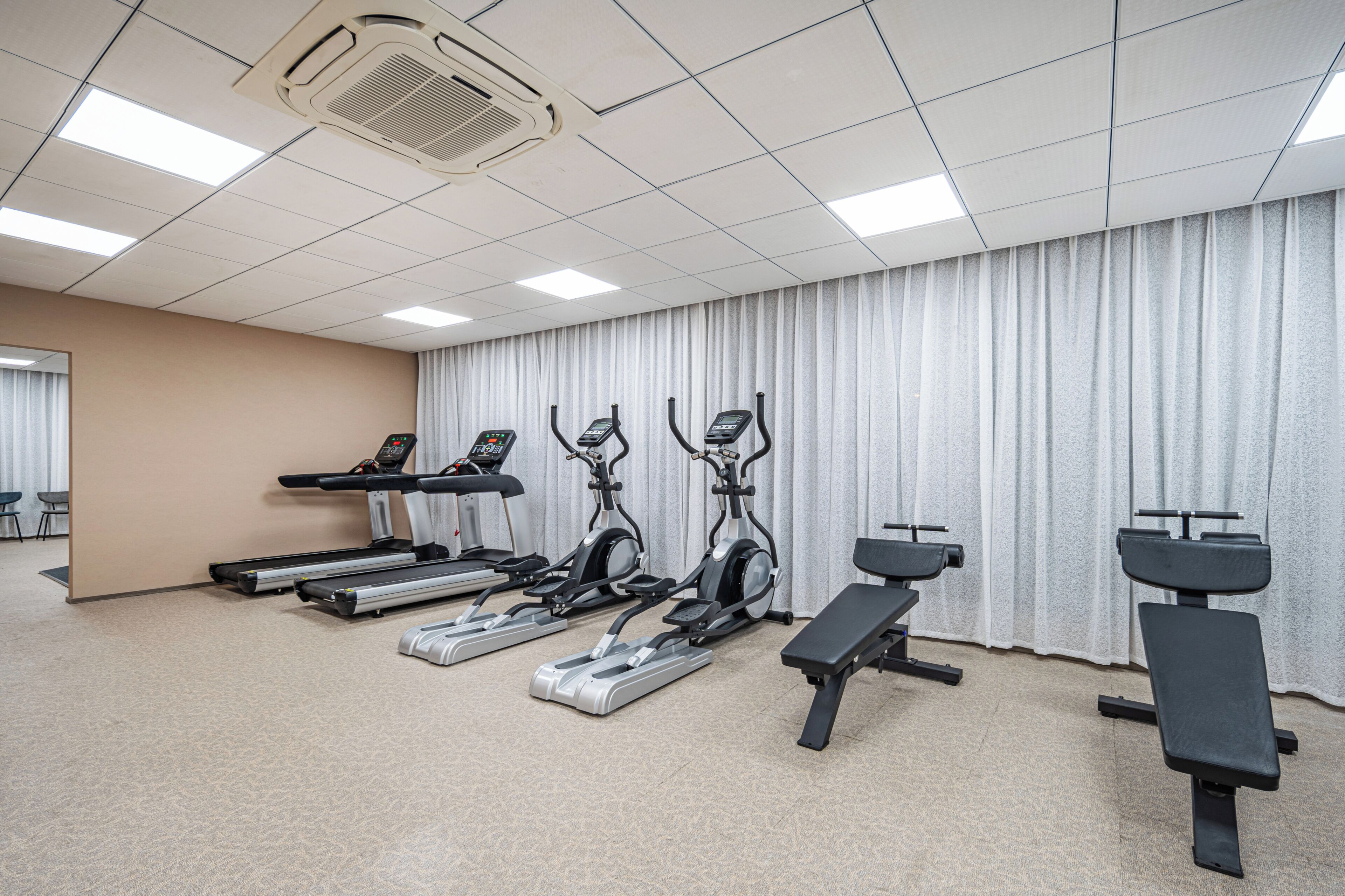 A gym with treadmills, elliptical machines, and weight benches.