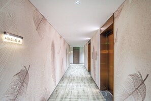 A hallway with a patterned floor, directional signs, and a door with a handle.