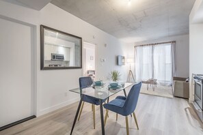 A modern living room with a glass dining table, blue chairs, a television, and a fireplace. - Cozy hidden gem in the heart of Montreal (Montréal)