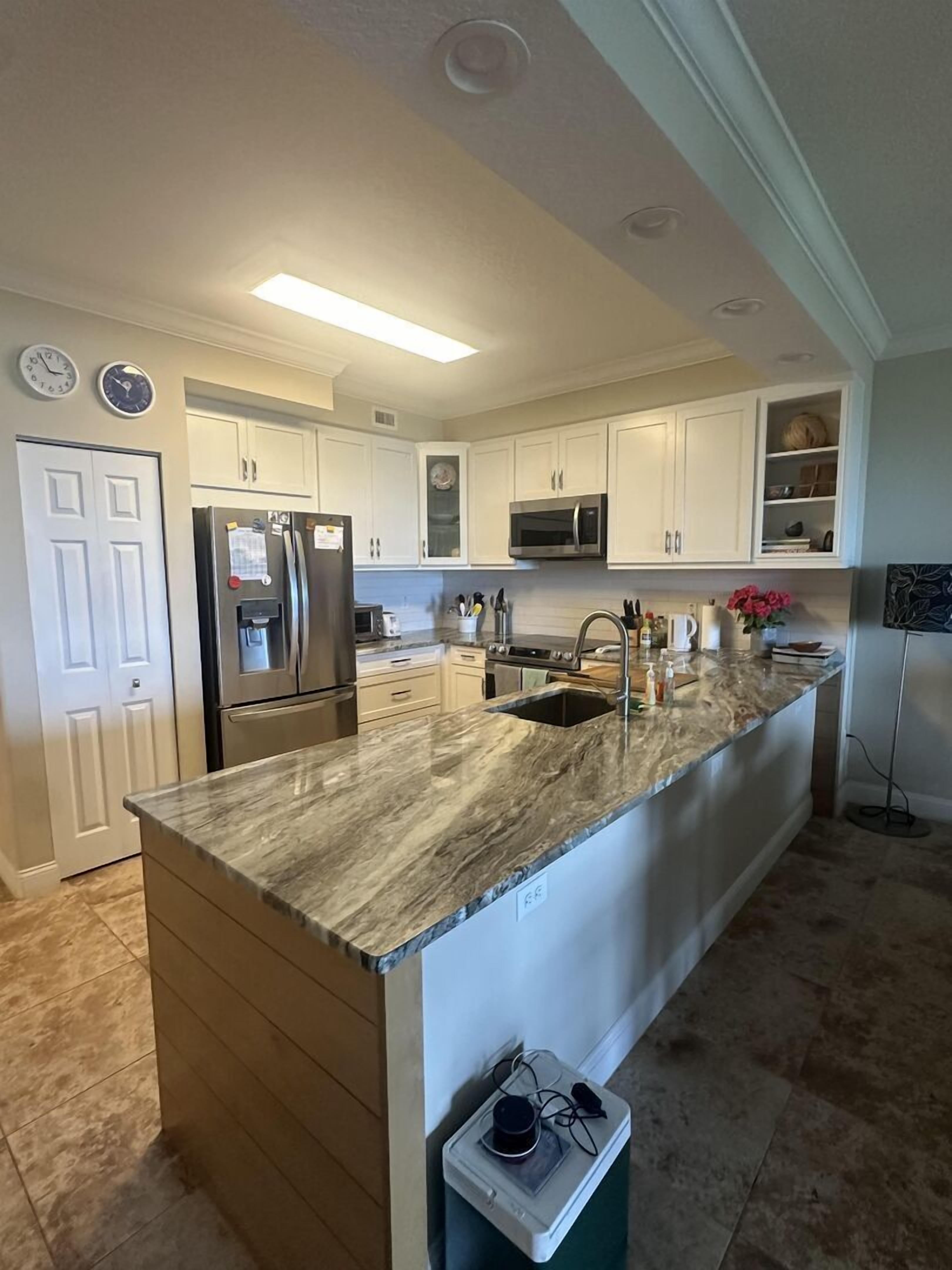 A modern kitchen with white cabinets, stainless steel appliances, a granite countertop, and a built-in microwave.