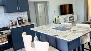 Une cuisine moderne avec des meubles de couleur bleu foncé, un plan de travail blanc et une cuisinière intégrée.