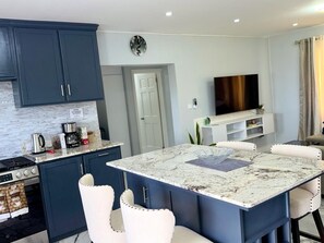 A modern kitchen with dark blue cabinets, a white countertop, and a built-in stove. - Careffe Gardens Stunning Breezy 2-bedroom Hilltop Villa (Monchy)