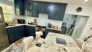 Une cuisine moderne avec des meubles de couleur sombre, un plan de travail en marbre et une cuisinière intégrée.