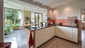 A modern kitchen with a large island, a dining area with a view, and a living space with a large window. - 3 bedroom beautiful home in Steenenkamer (Steenenkamer)
