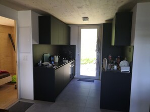 Eine kompakte Küche mit einer Tür zum Balkon, einer kleinen Essecke und einer sichtbaren Steckdose.
