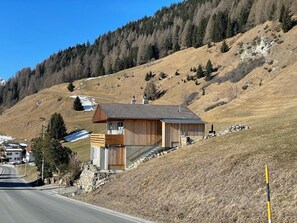 Ein modernes Haus mit geneigtem Dach, Holzfassade und Steinunterbau.