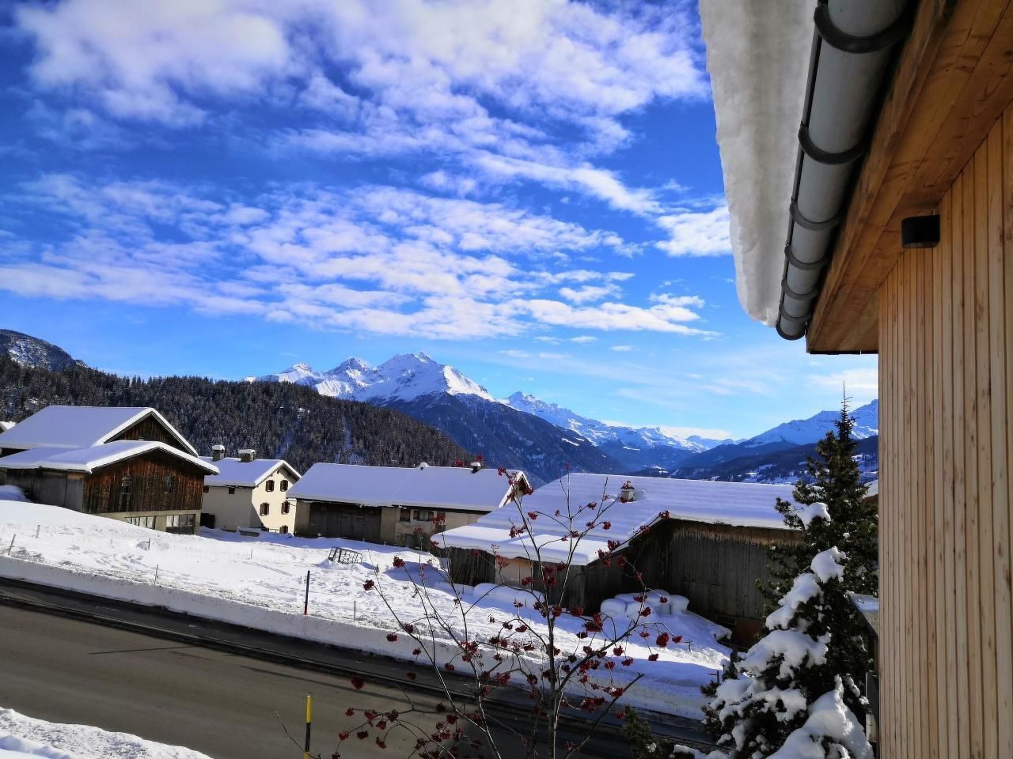 Un pueblo montañoso cubierto de nieve, con edificios de madera y cielo despejado.