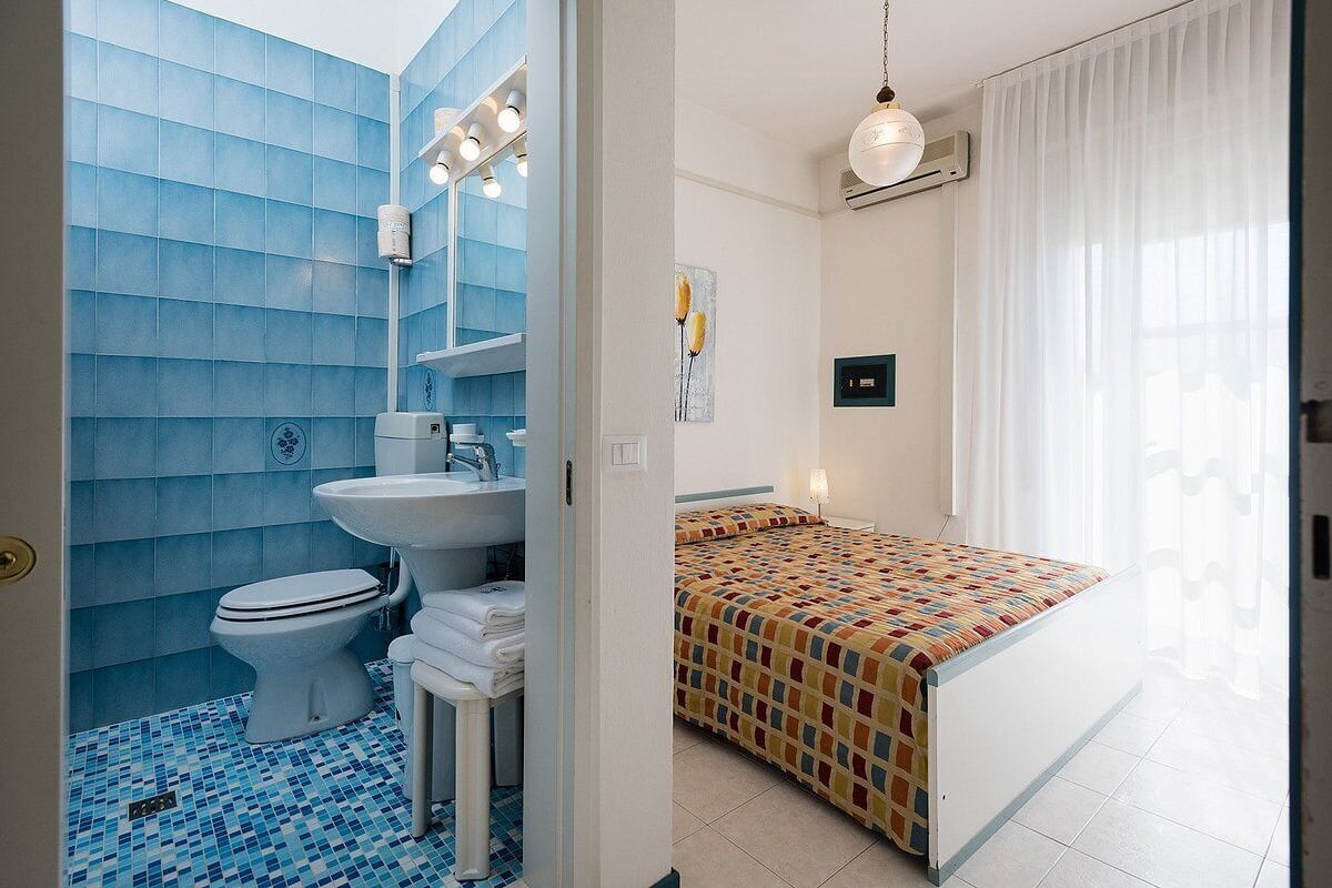 A bathroom with a toilet, sink, and blue tiled walls.