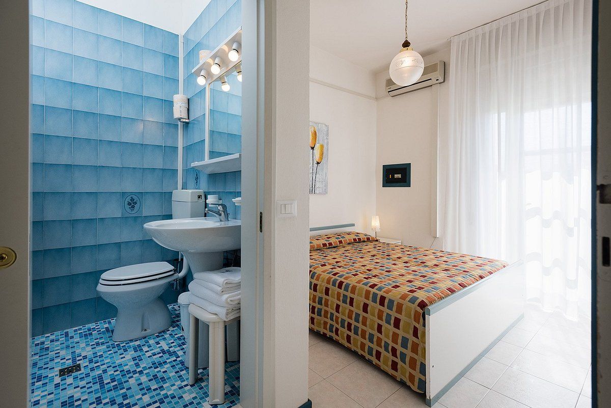 A bathroom with a toilet, sink, and blue tiled walls.
