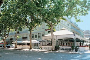 A hotel with outdoor seating, a white facade, and a sign for 'Apartment Park.' - Aparthotel Pineda (San Michele al Tagliamento)