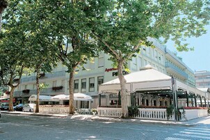 Un hotel con posti a sedere all'aperto, facciata bianca e insegna con la scritta 'Apartment Park'.