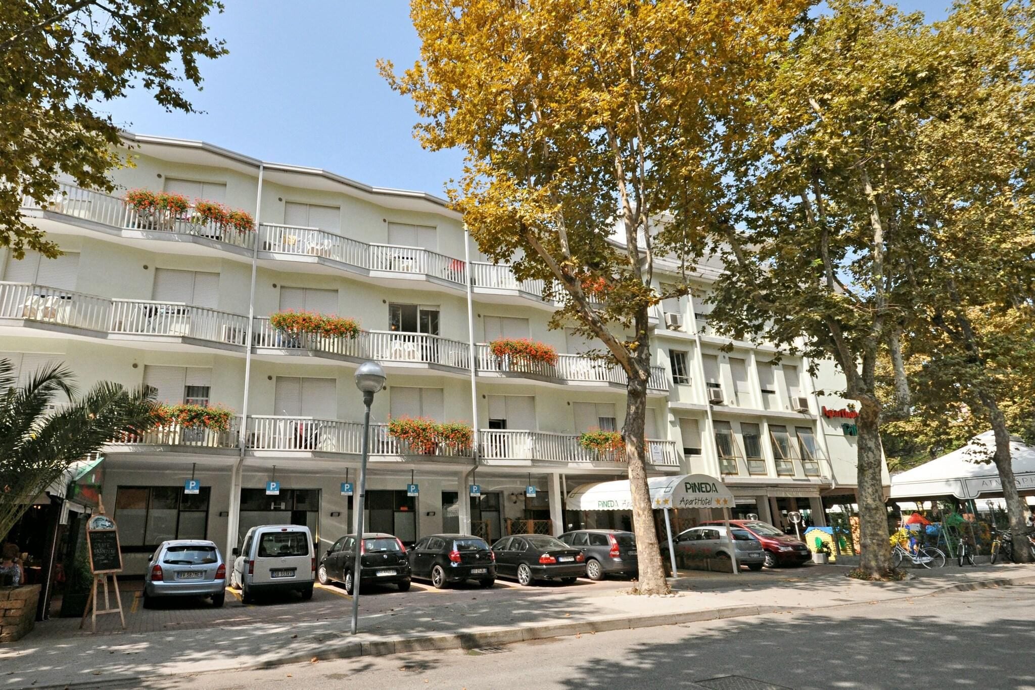 Un hotel de varios pisos con balcones, un estacionamiento y una fachada comercial.