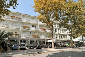 Un hôtel à plusieurs étages doté de balcons, d’un parking et d’une devanture de magasin.