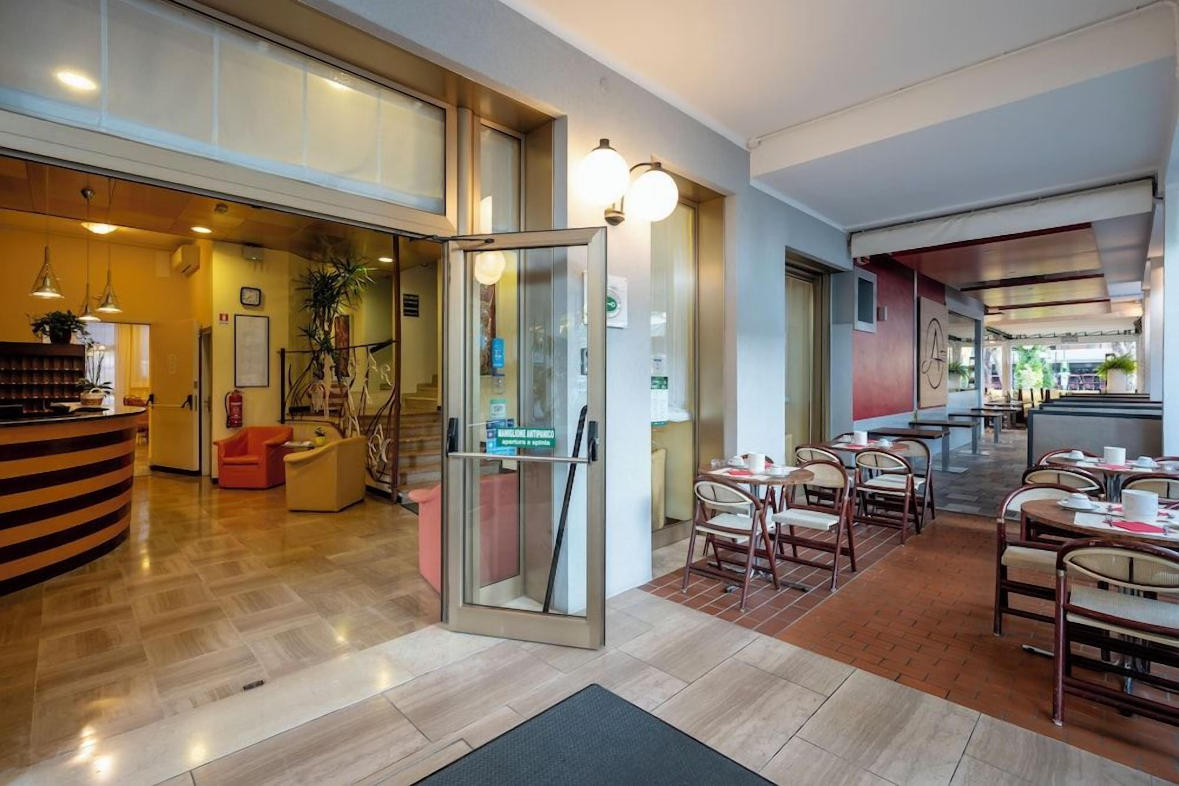 Un hall d’hôtel comprenant un comptoir d’accueil, un espace salon et un escalier menant à un étage supérieur.