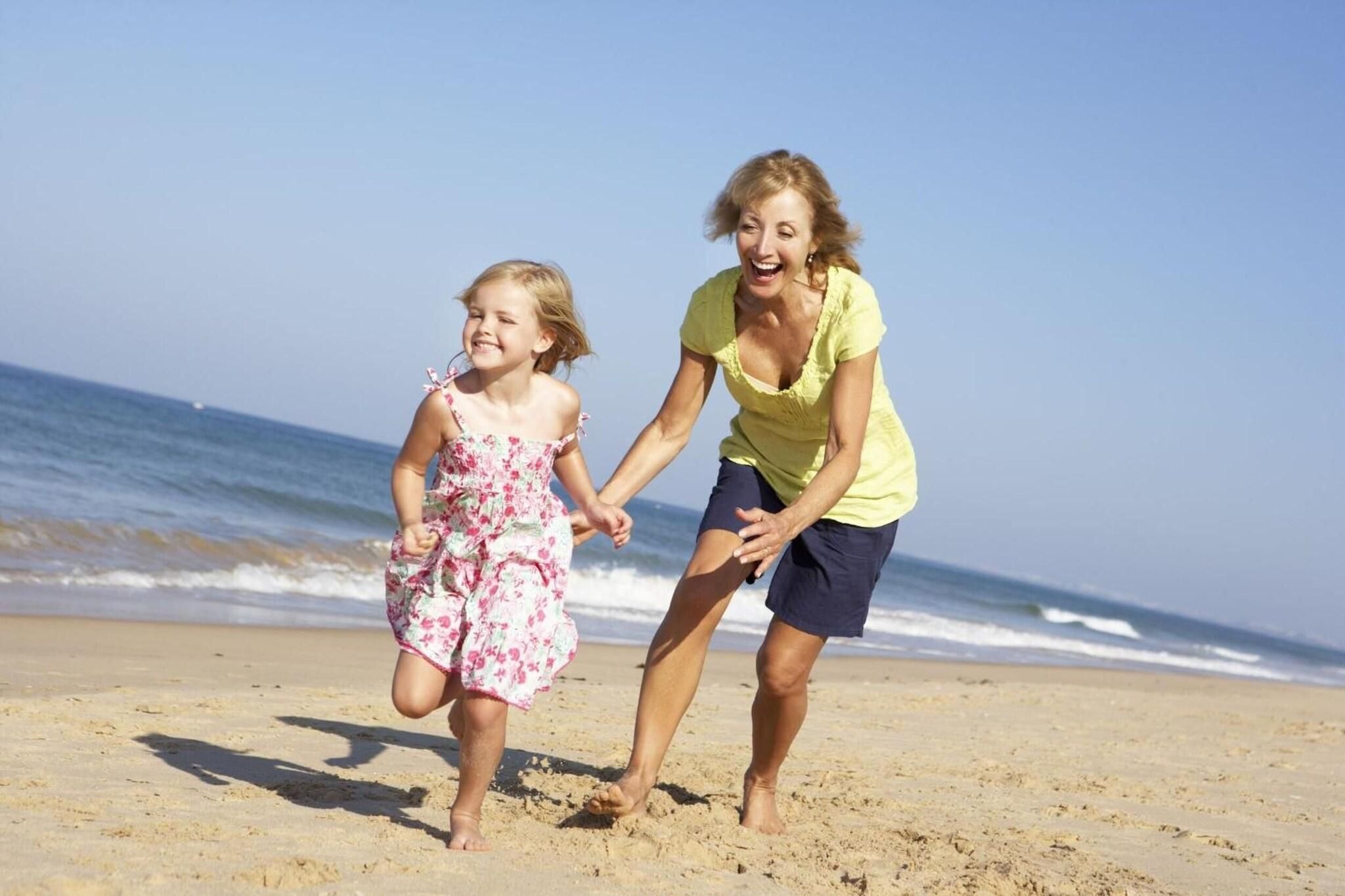 Eine Strandansicht, auf der eine Person und ein Kind Händchen halten.