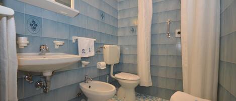 A bathroom with a sink, bidet, toilet, and shower curtain.