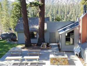 A building with a patio area, picnic tables, and a stone fireplace. - Updated 2B/2BA at Canyon Lodge- Jacuzzi & Parking! (Mammoth Lakes)
