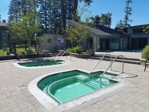 A pool area with two pools, a safety sign, and a building in the background. - Updated 2B/2BA at Canyon Lodge- Jacuzzi & Parking! (Mammoth Lakes)