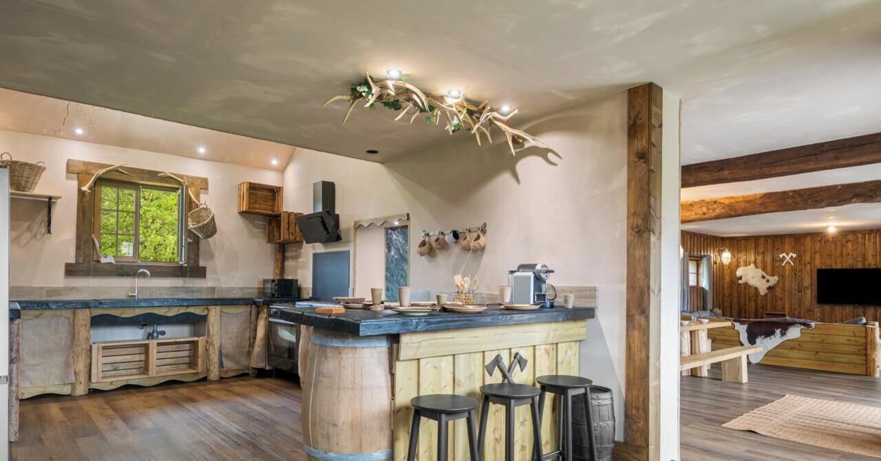 A rustic kitchen with a wooden island, bar stools, and a large window.