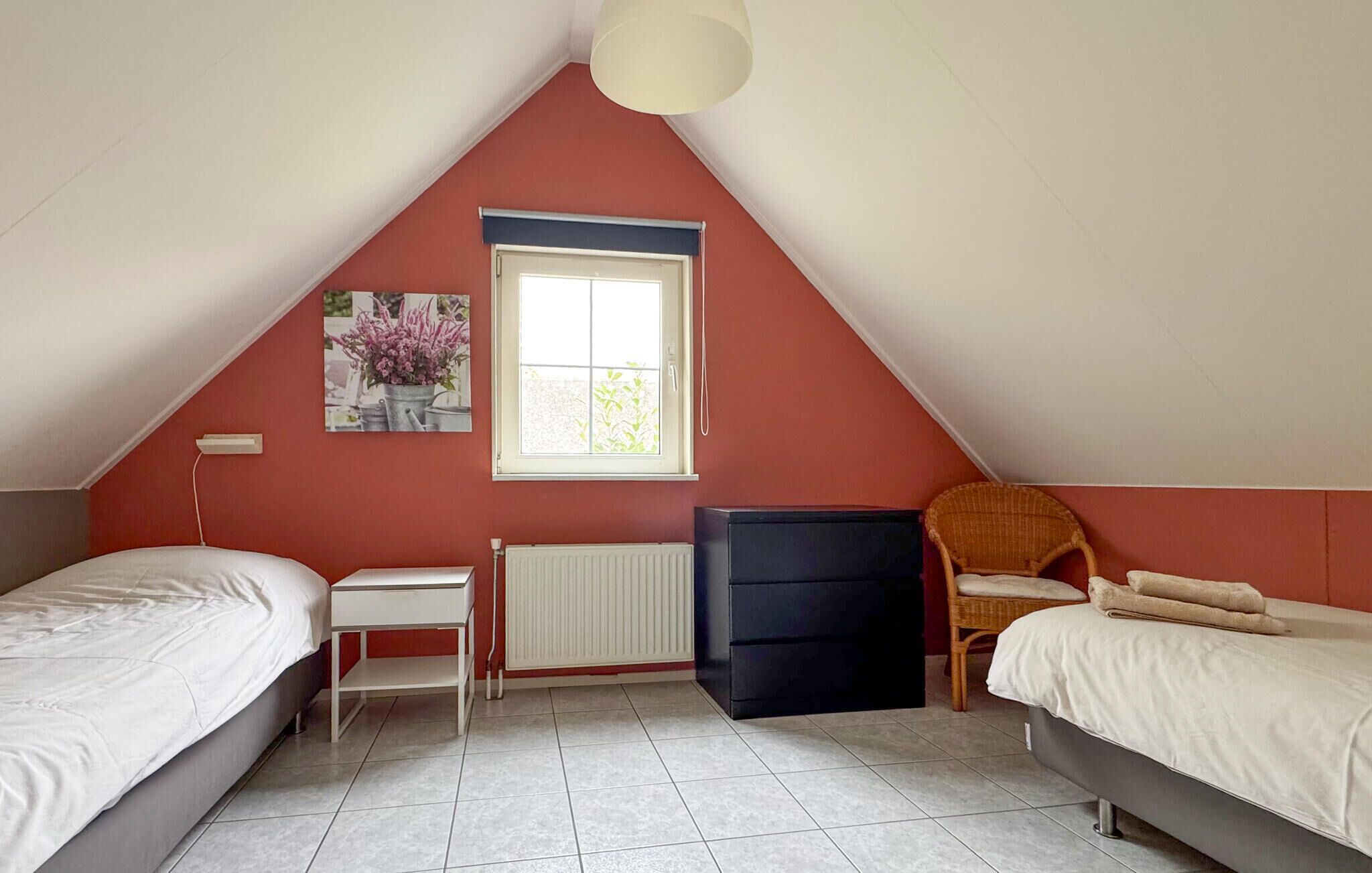 A bedroom with two beds, a radiator, a window, and a picture on the wall.