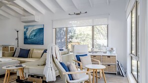 Ein modernes Wohnzimmer mit einer Couch, Sesseln, einem kleinen Tisch und einem großen Fenster mit Blick.