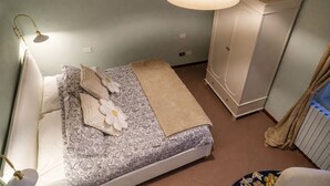 Un dormitorio con cama, armario, lámpara de noche y radiador.