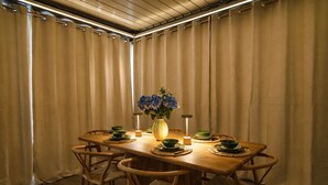 Un comedor con una mesa de madera, platos verdes y un jarrón de flores.
