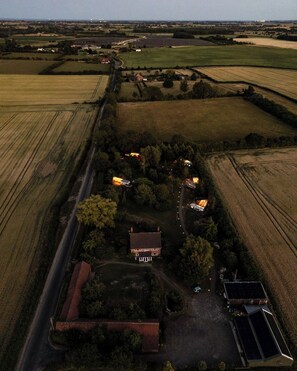 Vue aérienne d’une propriété rurale comprenant des champs, une maison principale et un panneau solaire.