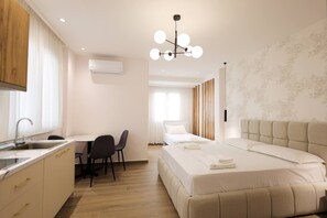 Ein modernes Hotelzimmer mit Küchenzeile, einem Bett, einem Schreibtisch und einem Stuhl.