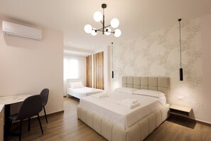 Ein modernes Hotelzimmer mit einem Bett, einem Nachttisch und einem Schreibtisch mit Stühlen.