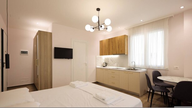 Hotellihuone, jossa on sänky, televisio, pieni keittiö ja ruokailutila.