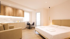 Een moderne hotelkamer met een bed, een bank, een eettafel en een kitchenette.