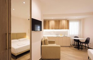A compact hotel room with a bed, a sofa, a small kitchen area, and a TV. - Cozy Apartment 06 in Durr s (Durrës)
