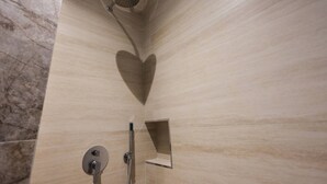 A shower with a heart-shaped design on the wall, a handheld showerhead, and a wall-mounted faucet. - Cozy Apartment 03 in Durr s (Durrës)