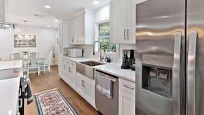 A modern kitchen with stainless steel appliances, white cabinetry, and a built-in dishwasher. - Pet Friendly Retreat | 3BR w/ Sunroom, Spacious Kitchen + Close to Beach (Saint Simons Island)