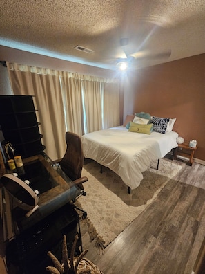 Una habitación de hotel con cama, escritorio, silla, mesita y lámpara.