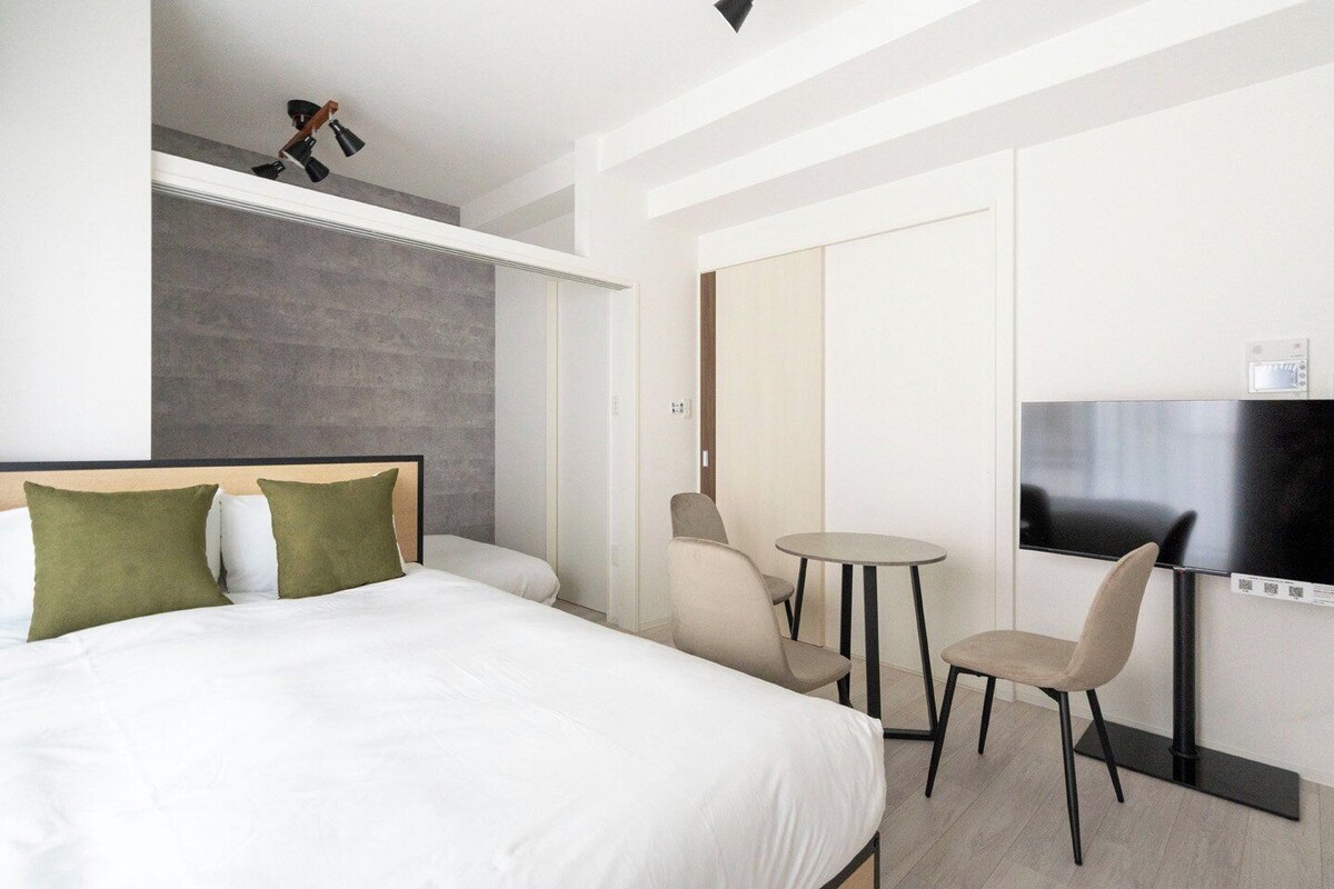 A hotel room with a bed, a TV, a small table, and chairs.