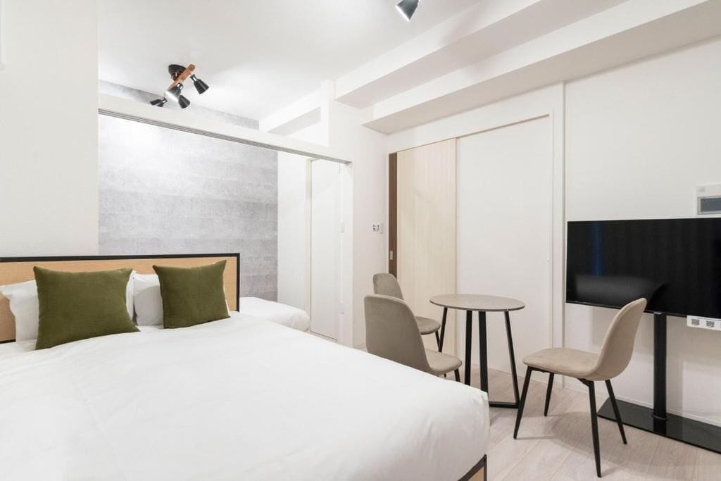 A hotel room with a bed, two chairs, a small round table, and a TV.