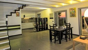 Un interior moderno con escalera, comedor, cocina y ventanas amplias.