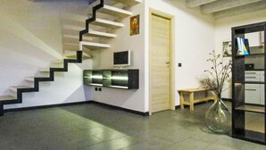 Un interior moderno con una escalera, un televisor de pantalla plana, una puerta de madera y una estantería.