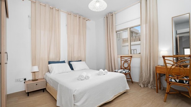 Ein Schlafzimmer mit Bett, Nachttisch, Sessel und Schreibtisch mit Stuhl.