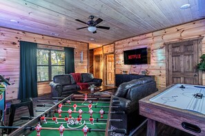 A cozy room with a foosball table, a leather sofa, a television, and a pool table. - Just Remodeled Cabin w/ 4-Game Arcade, Hot Tub & Peloton | 4 Mi to Dollywood! (Pigeon Forge)